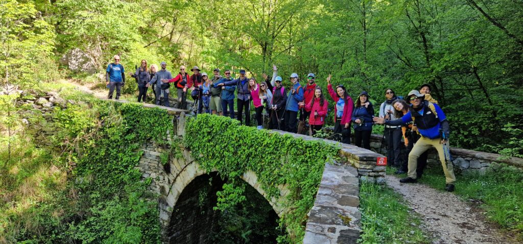 Ομάδα πεζοπόρων των Trekkers δίπλα σε κόκκινη σήμανση μονοπατιού σε πέτρινο γεφύρι